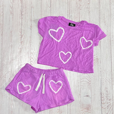 this picture shows this set together the neon purple shorts with the neon purple shirt. each with white tie dye hearts on them