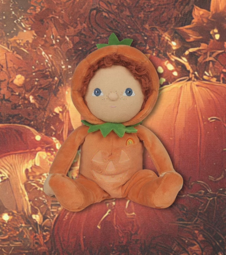 Plush toy dressed as a pumpkin with a textured autumn background