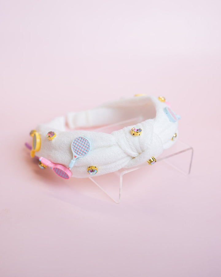 White top knot headband with tennis charms on it  on a pink background