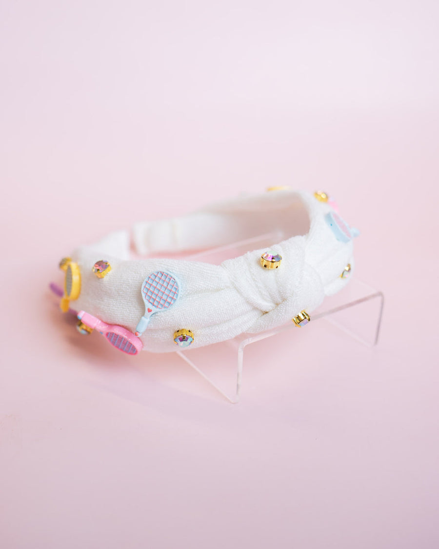 White top knot headband with tennis charms on it  on a pink background