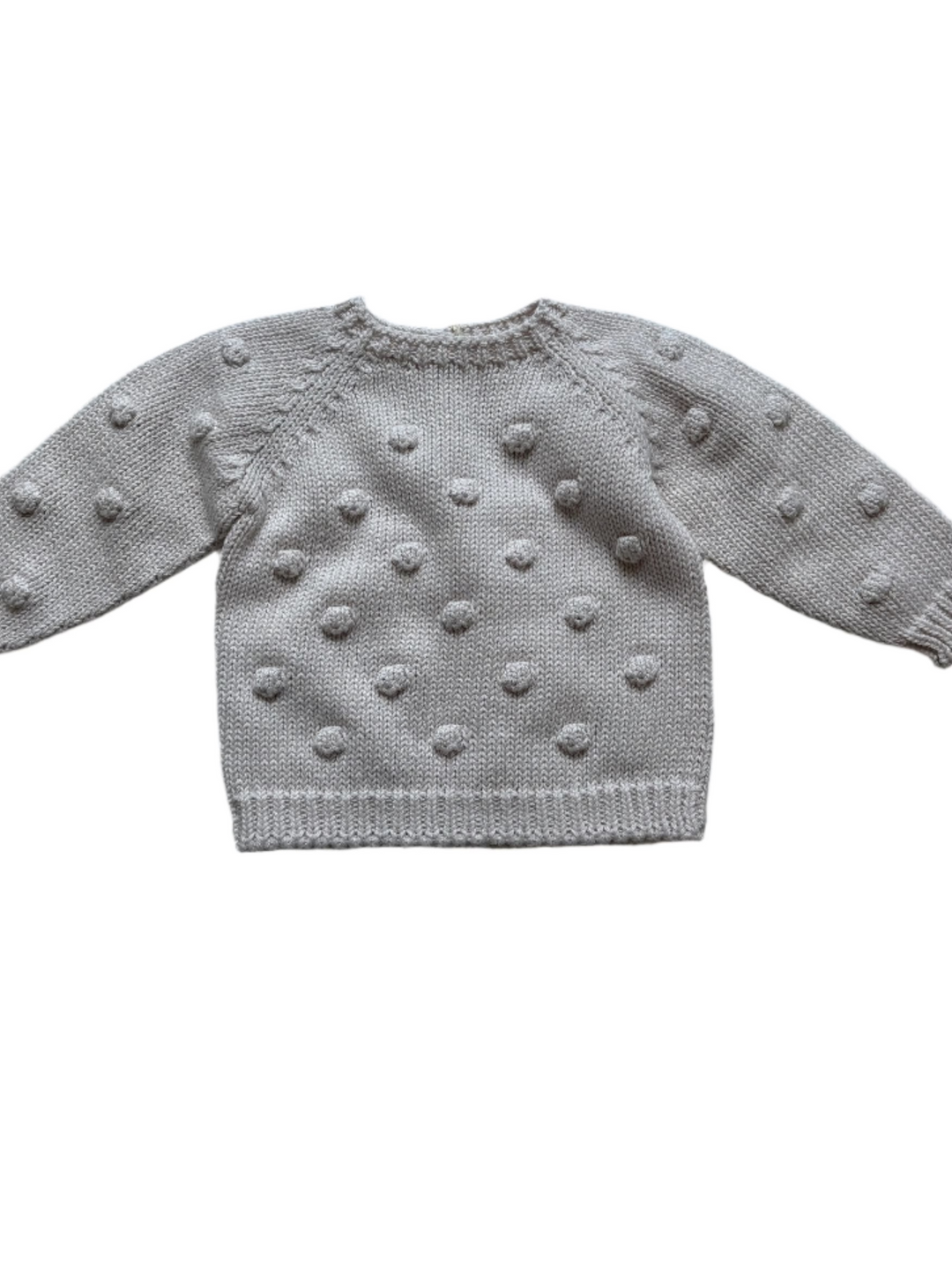 baby sweater with pom poms on the sweater. creme color. 