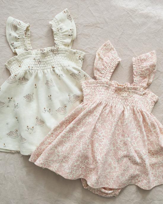two smocked dresses, one pink floral and one beige with tiny swans. 
