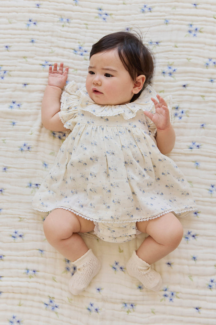 Baby in a floral dress lying on a textured surface