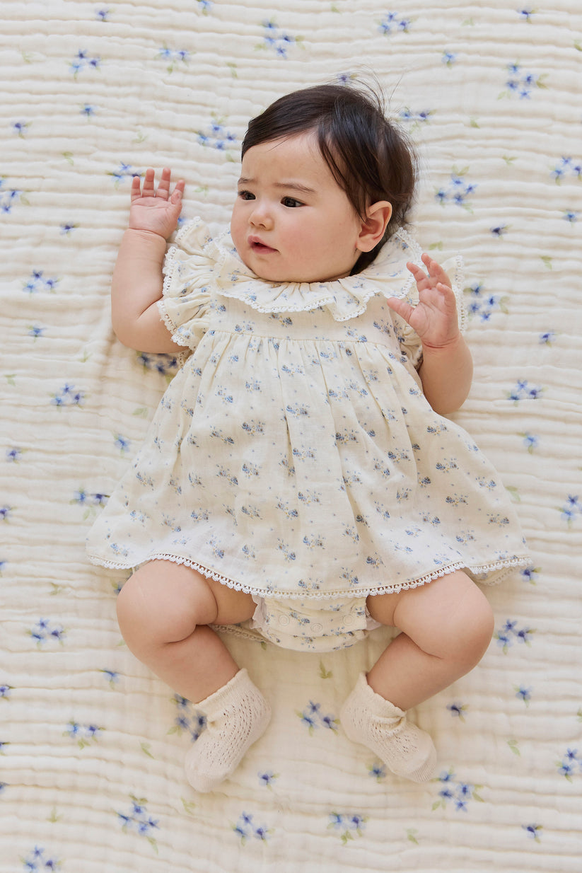 Baby in a floral dress lying on a textured surface