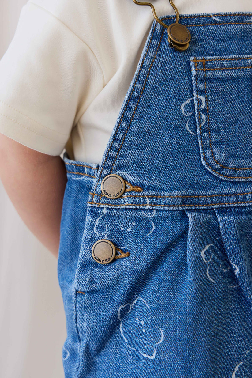 Close-up of blue denim overalls with buttons on a plain background