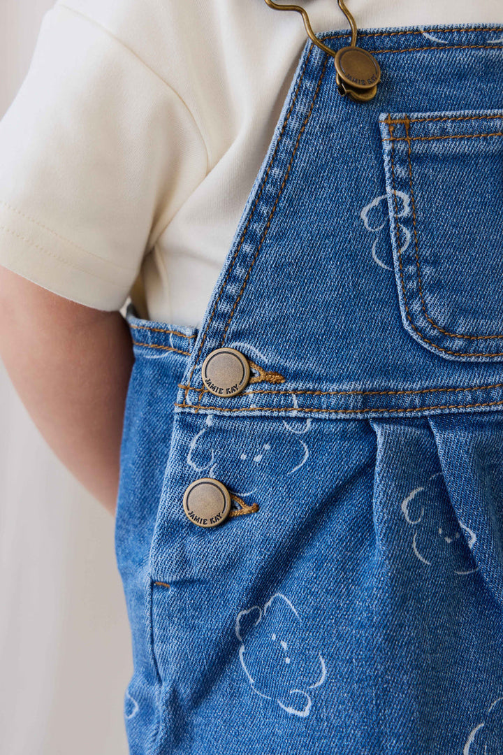 Close-up of blue denim overalls with buttons on a plain background