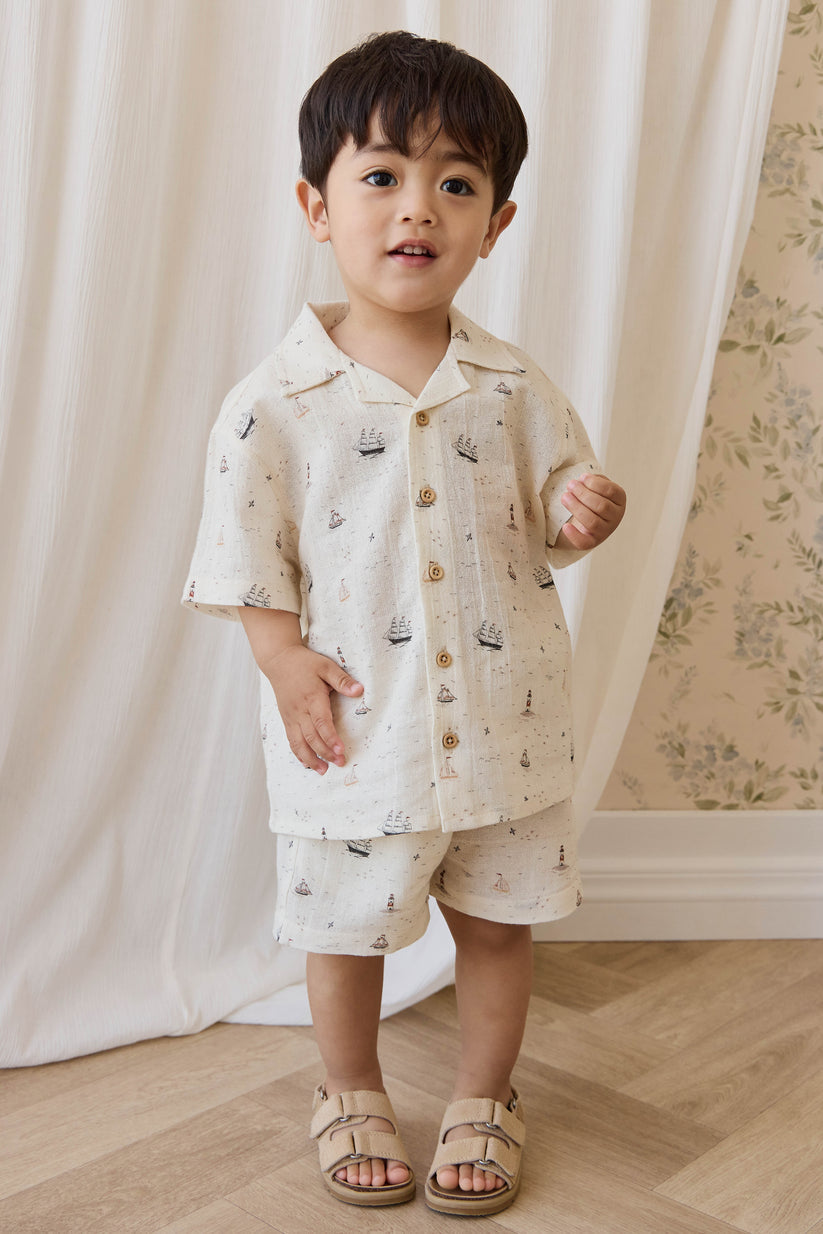 Child wearing a nautical patterned shirt and shorts set with a neutral background