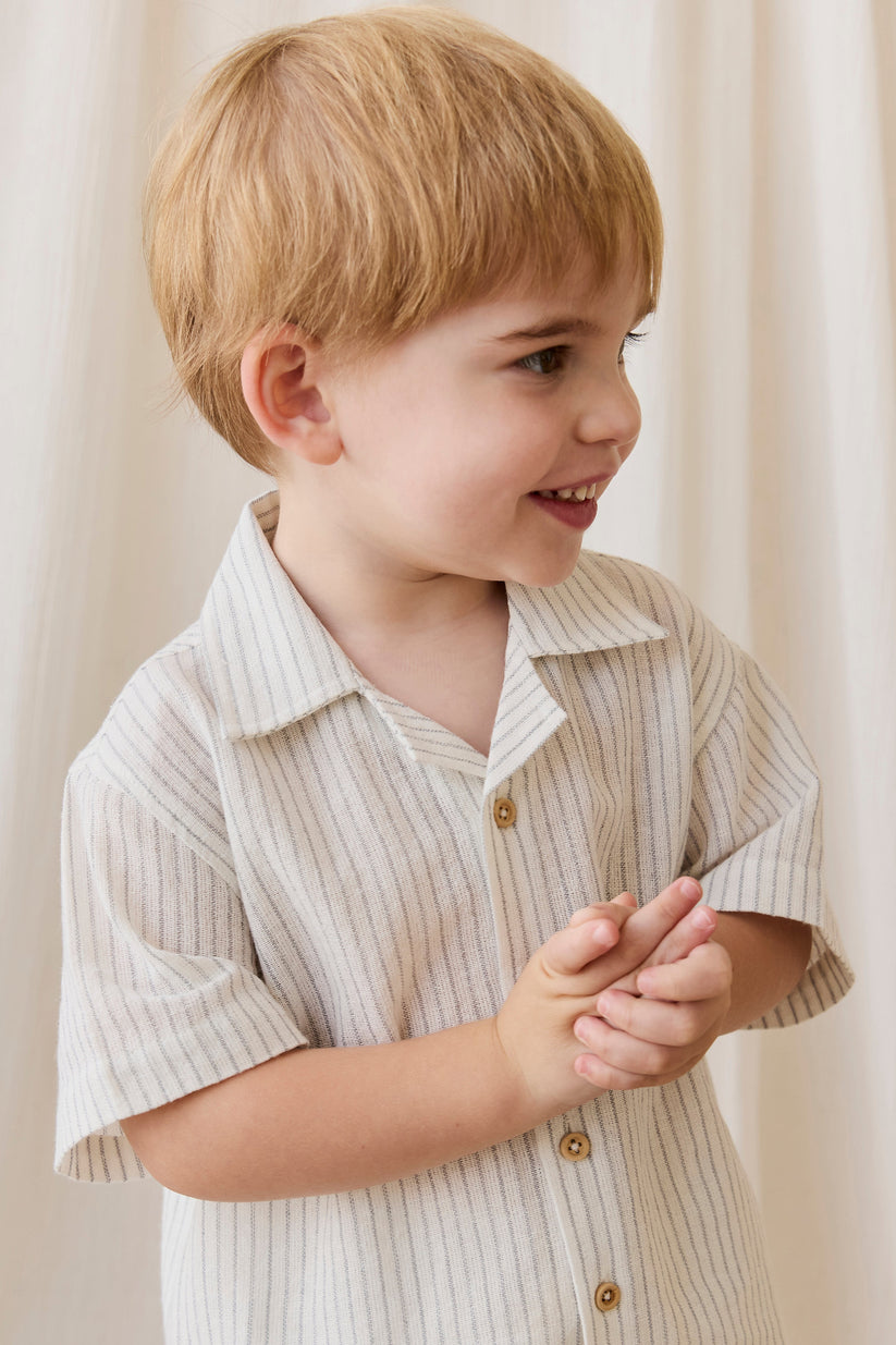 young boy wearing a beige collared shirt with pinstripes
