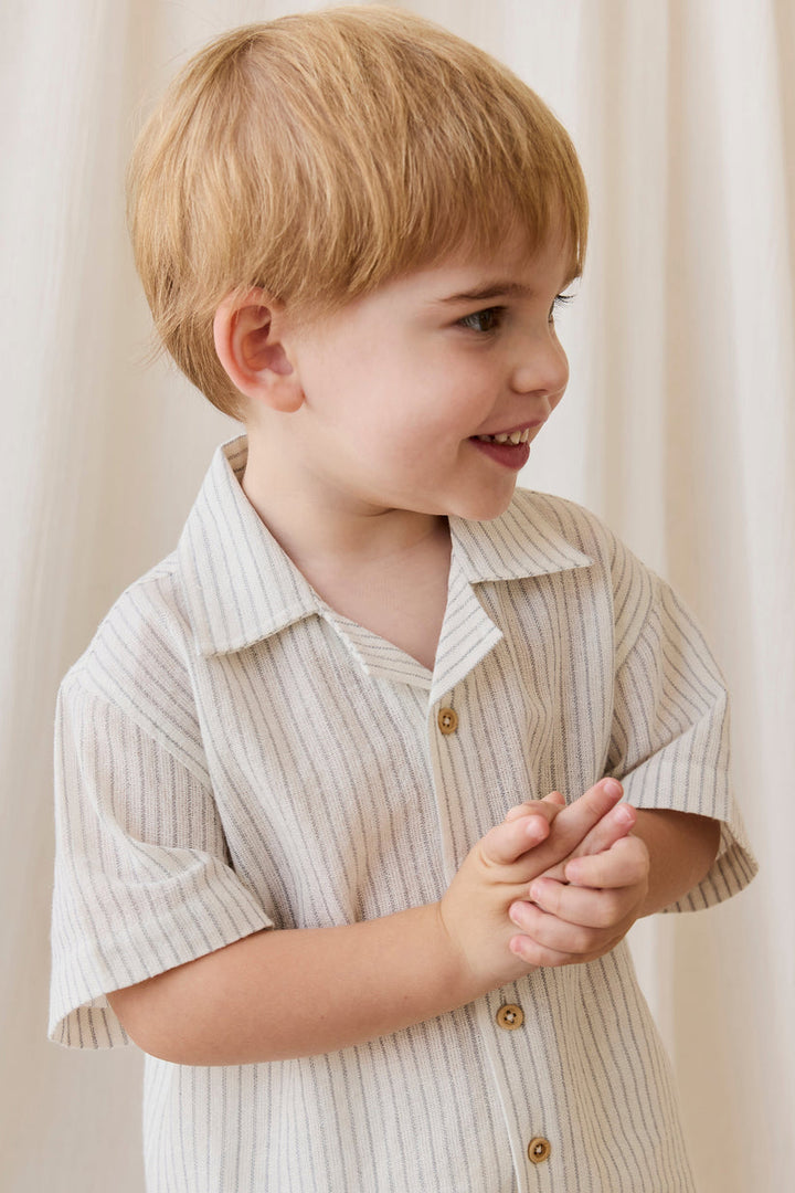 young boy wearing a beige collared shirt with pinstripes