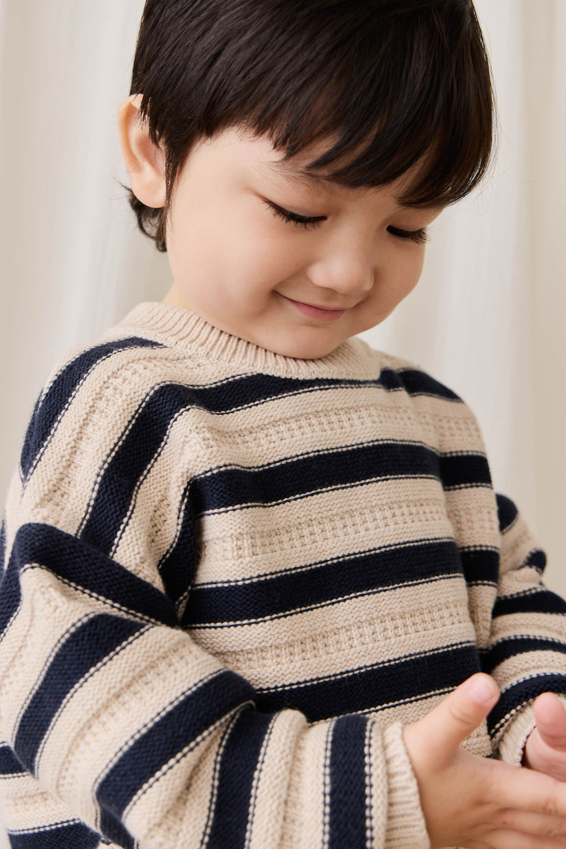 Child wearing a striped sweater against a neutral background