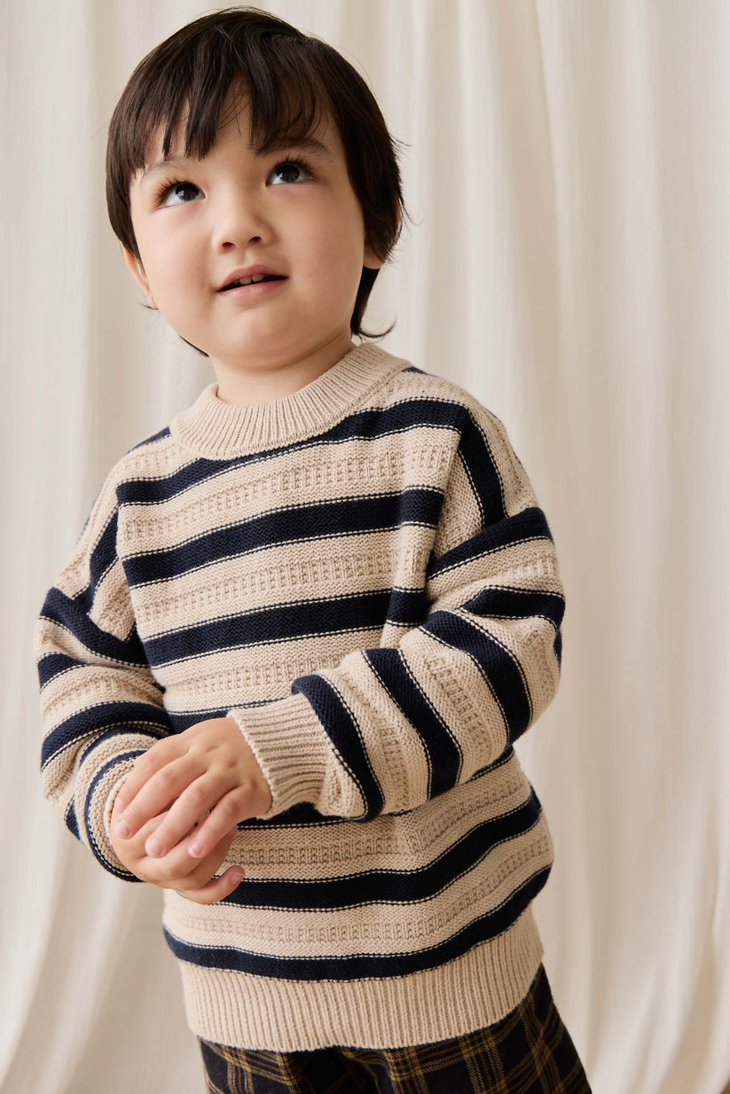Child wearing a striped sweater against a plain background