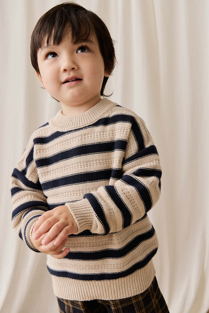 Child wearing a striped sweater against a plain background