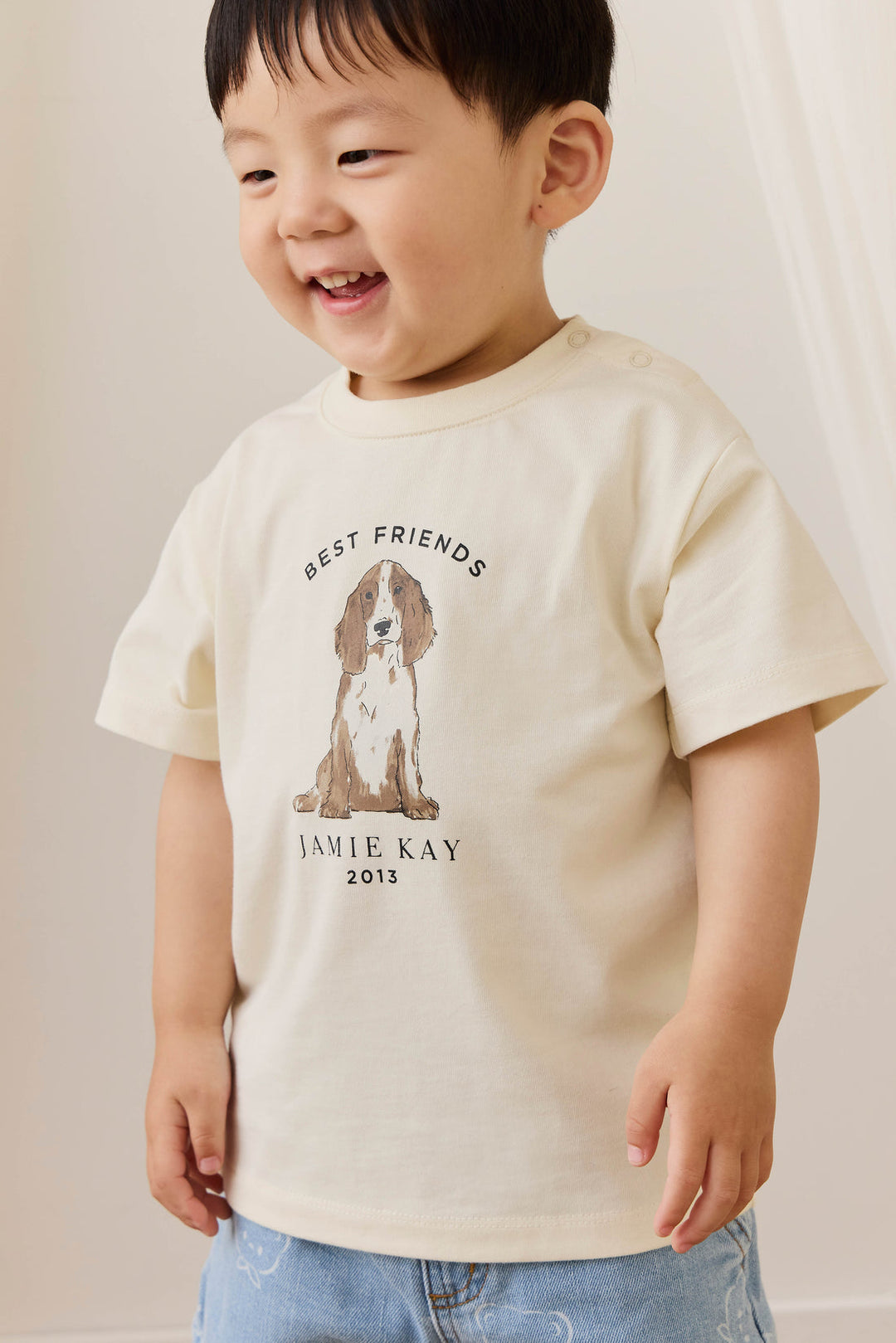 Child wearing a cream t-shirt with a dog graphic and text, standing against a plain background