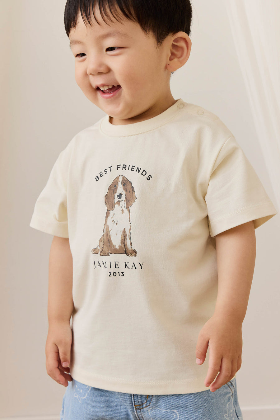 Child wearing a cream t-shirt with a dog graphic and text, standing against a plain background