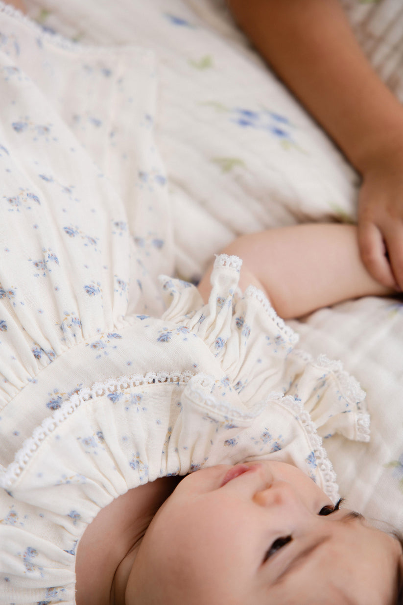 Baby lying on a textured blanket with a close-up of a dress hem.