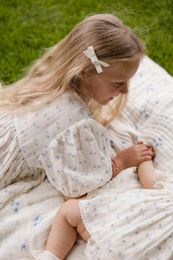 Young girl in a floral dress lying on a blanket outdoors