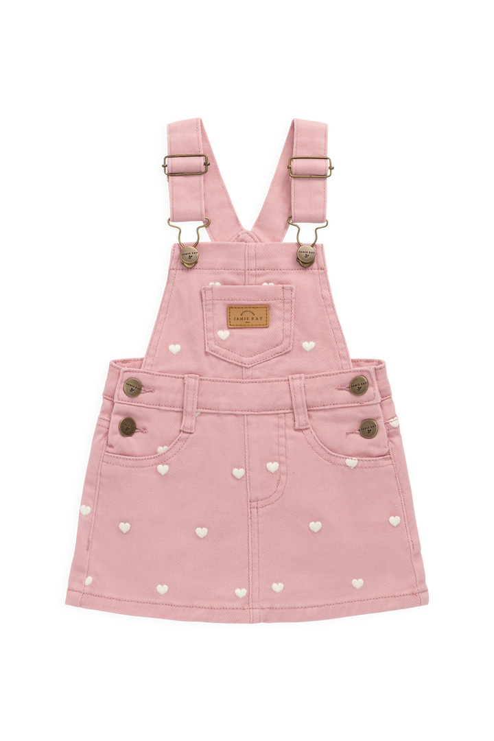 Pink denim pinafore dress with heart patterns on a white background