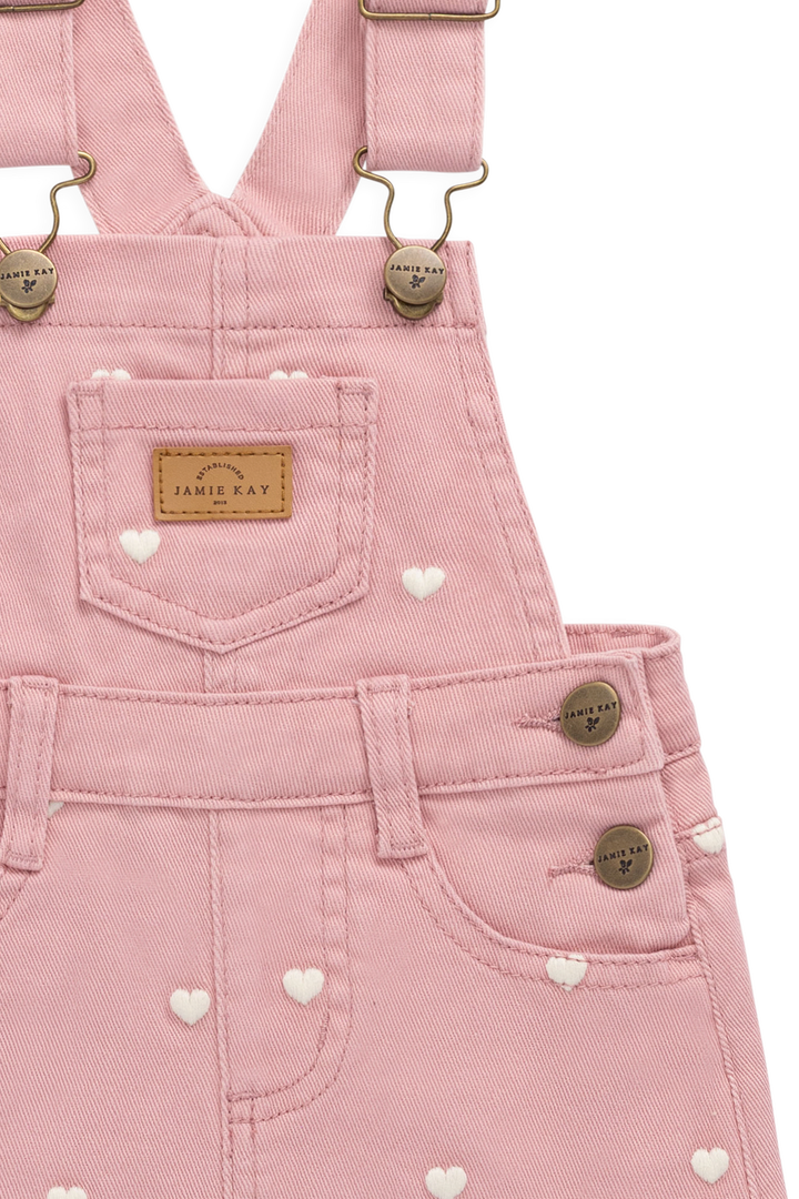 Pink denim overalls with heart patterns on a white background