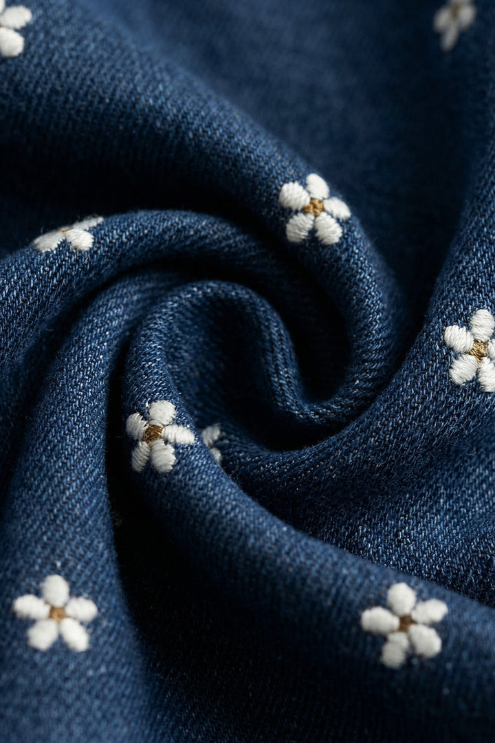 Close-up of denim blue fabric with white floral embroidery