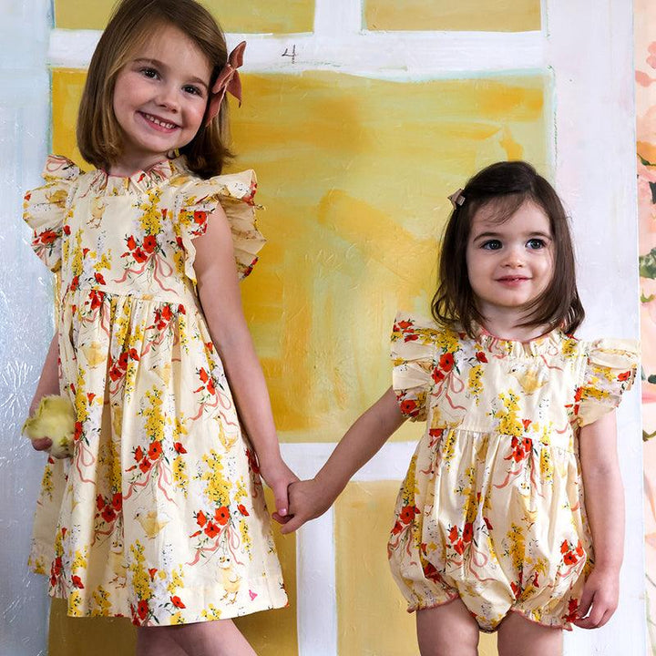 two little girls modeling the baby chick outfits, one dress with ruffle at collar and sleeves and little sister wearing the bubble with ruffle on sleeves. 