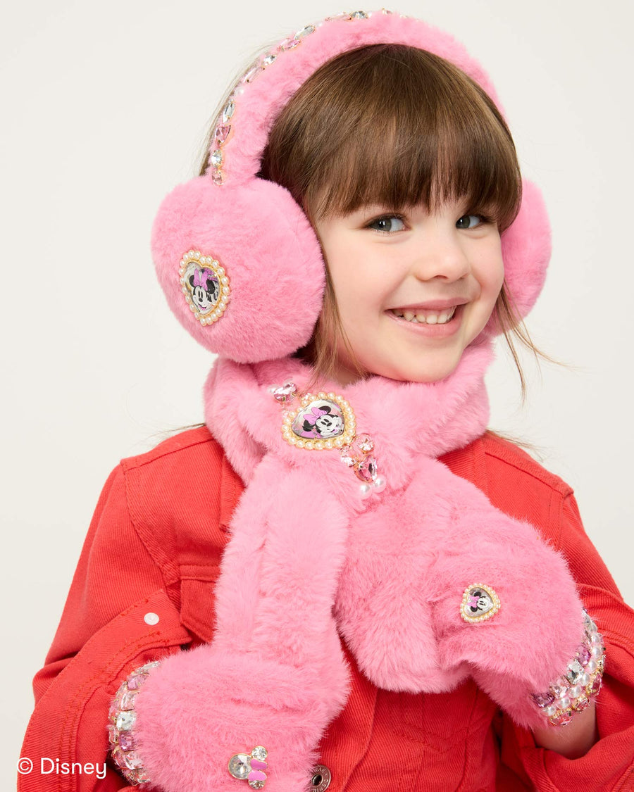 Child wearing pink Disney-themed earmuffs, scarf, and gloves on a white background