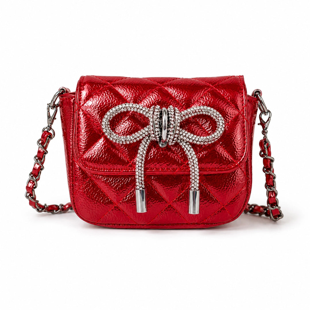 A red quilted leather shoulder bag with a large rhinestone-embellished bow on the front flap and a red-and-silver chain strap, shown on a plain white background.