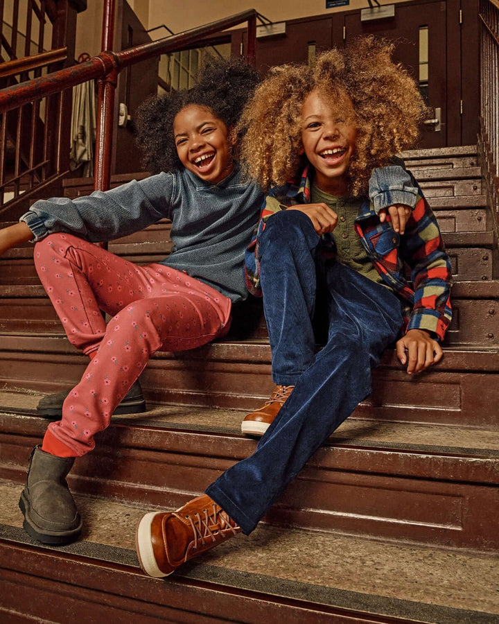 Two children sitting on a staircase, laughing and smiling.