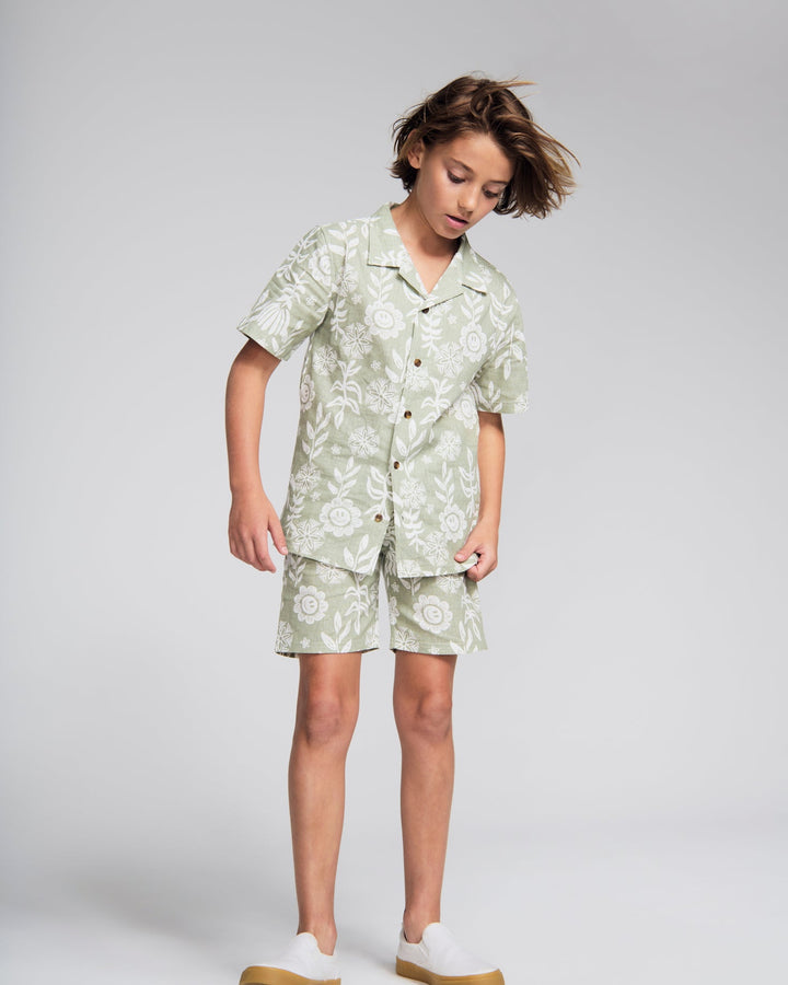 Child wearing a green floral outfit on a white background