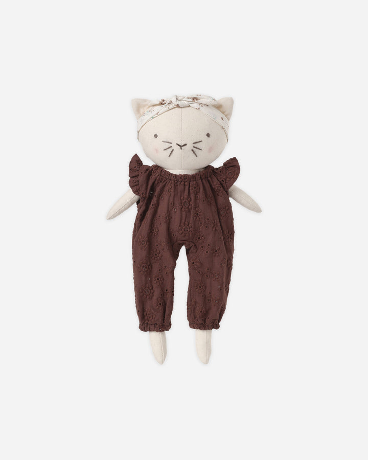 A plush cat doll with cream-colored fabric body, embroidered facial features, a matching cream headband with bow, and dark brown eyelet lace romper, centered on a light gray background.