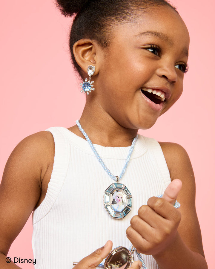 Child wearing sparkling jewelry against a pink background