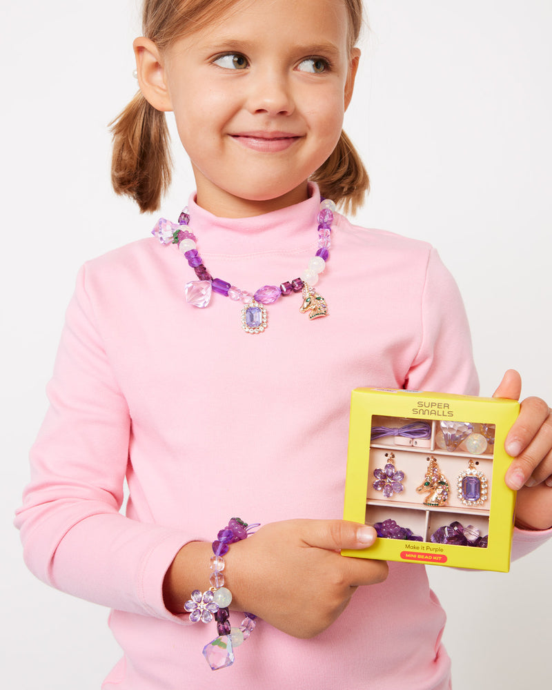 lilttle kid modeling the purple bead making kit. she is wearing a necklace and bracelet she can make in the kit- all of the elements are purple