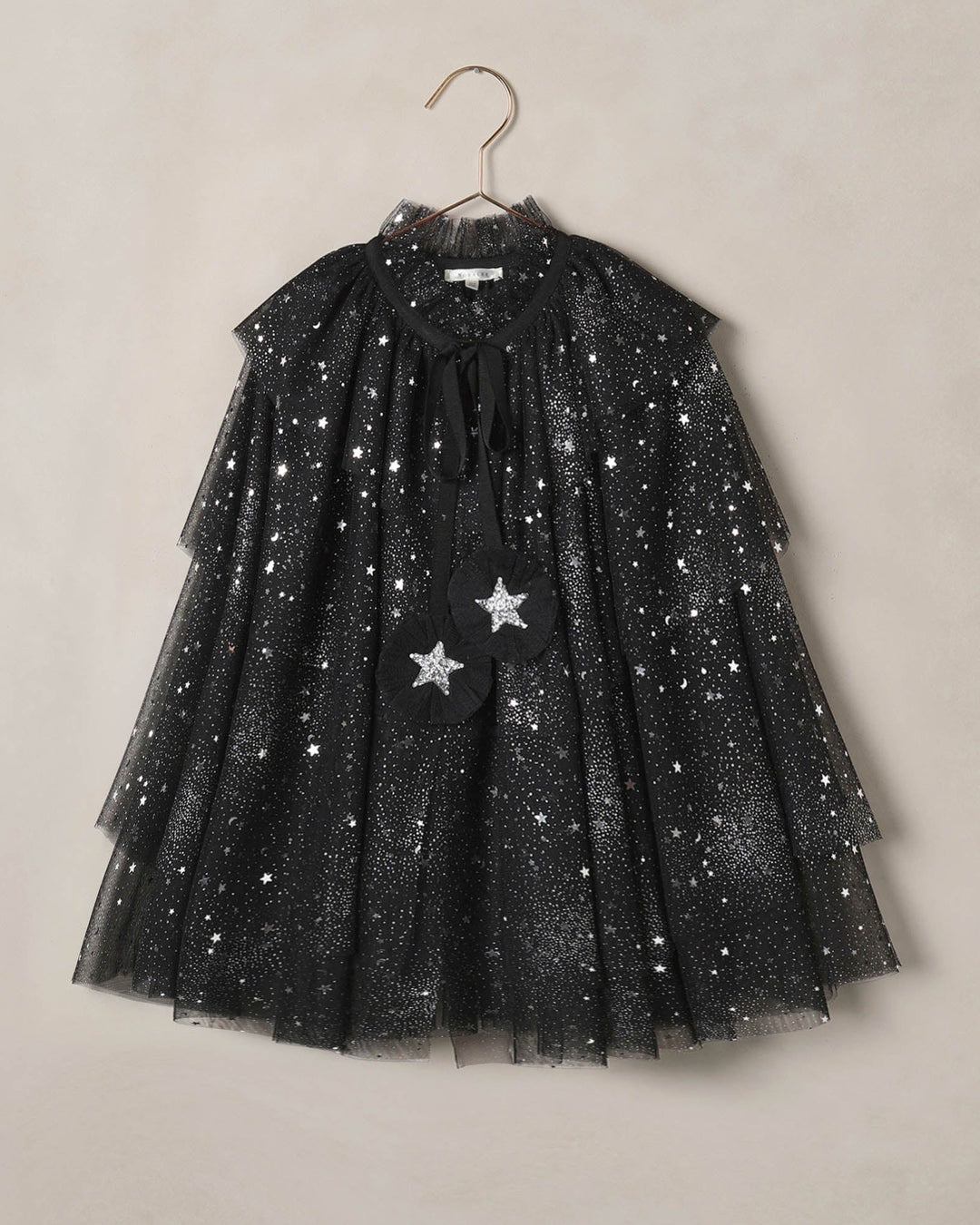 Black tulle dress with star patterns on a beige background