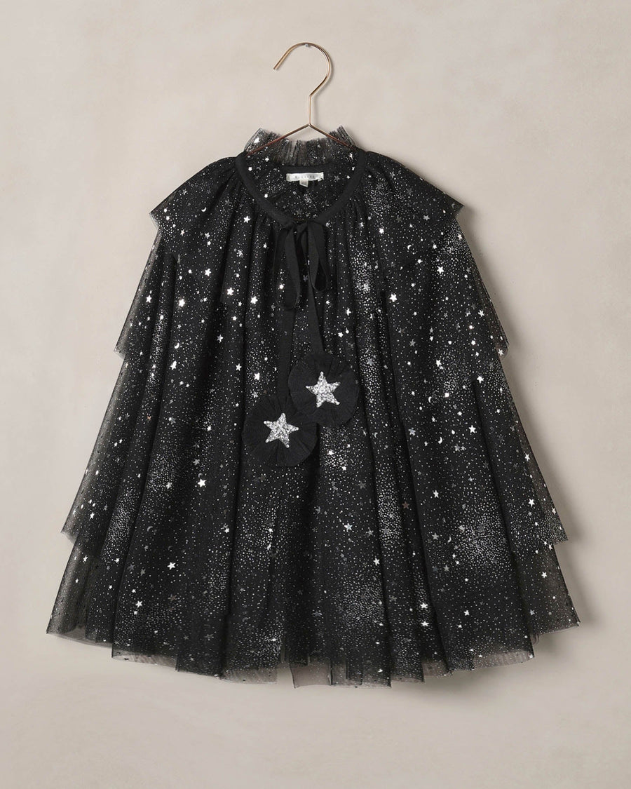 Black tulle dress with star patterns on a beige background