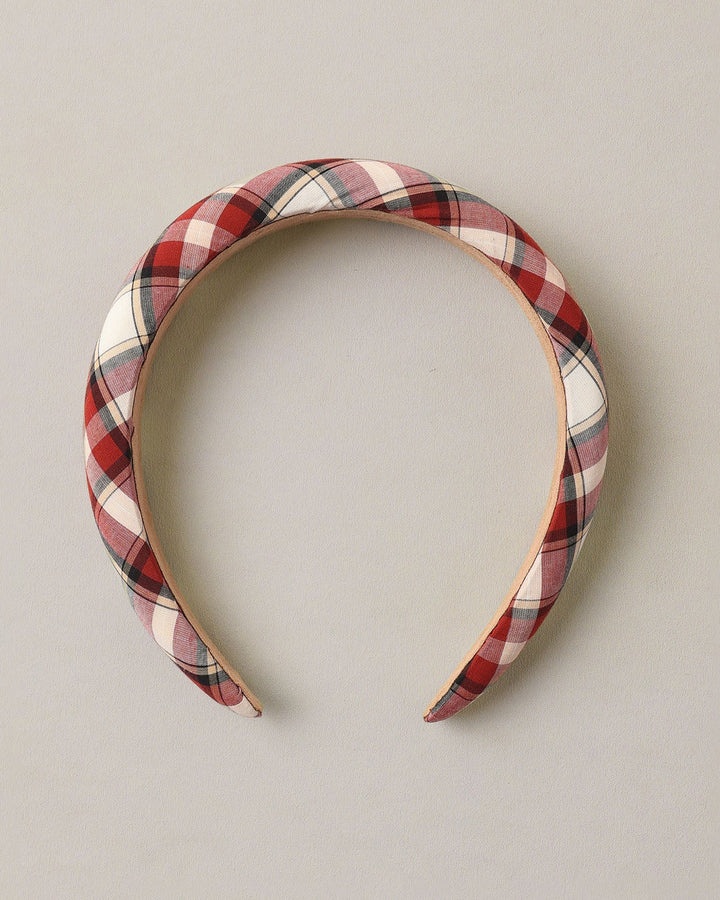 A padded fabric headband with a red, white, and black plaid pattern, displayed against a neutral light gray background.
