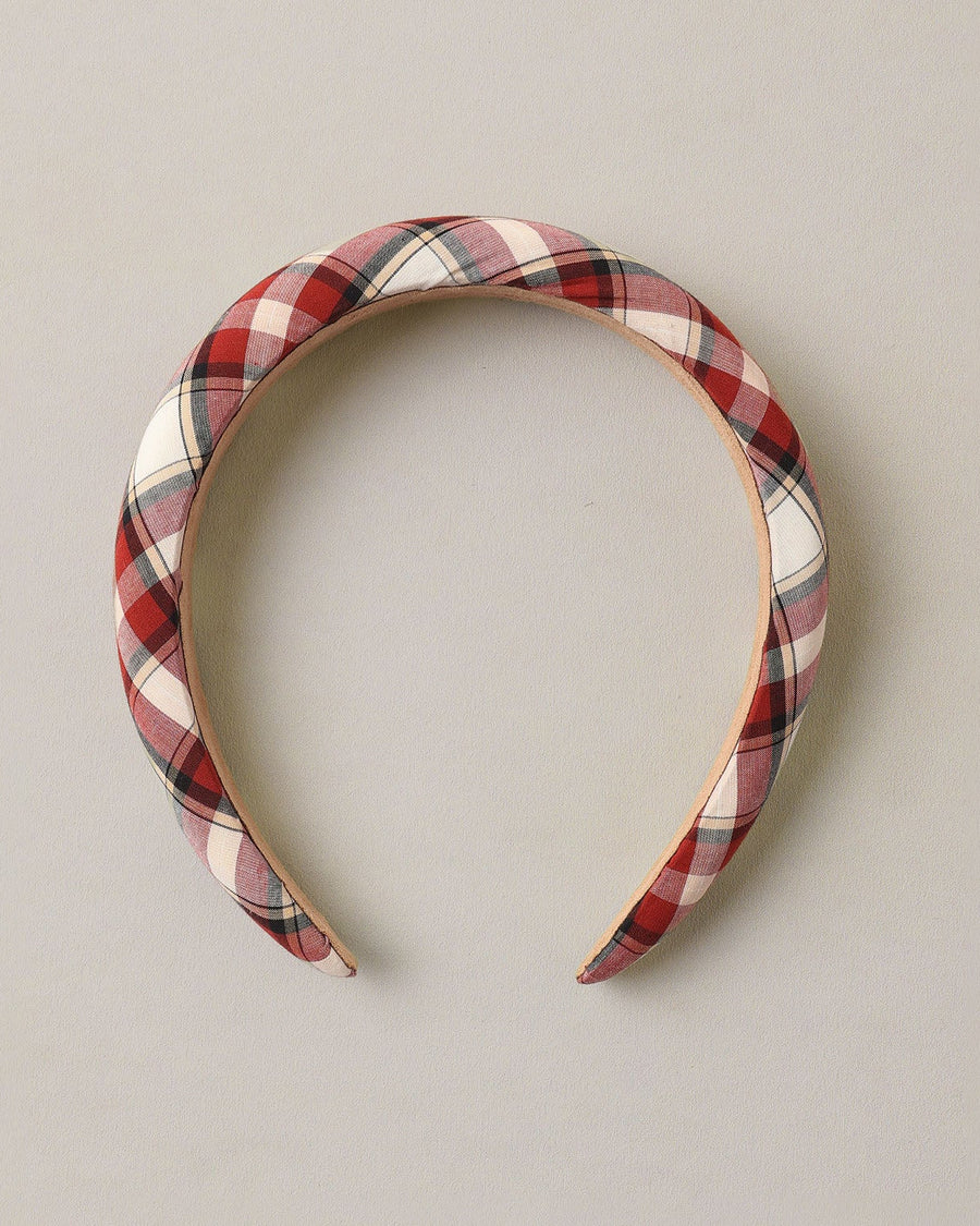 A padded fabric headband with a red, white, and black plaid pattern, displayed against a neutral light gray background.
