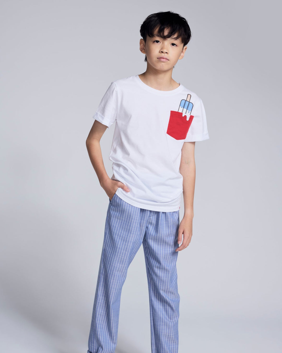 Child wearing a white t-shirt with a red pocket design on a plain background