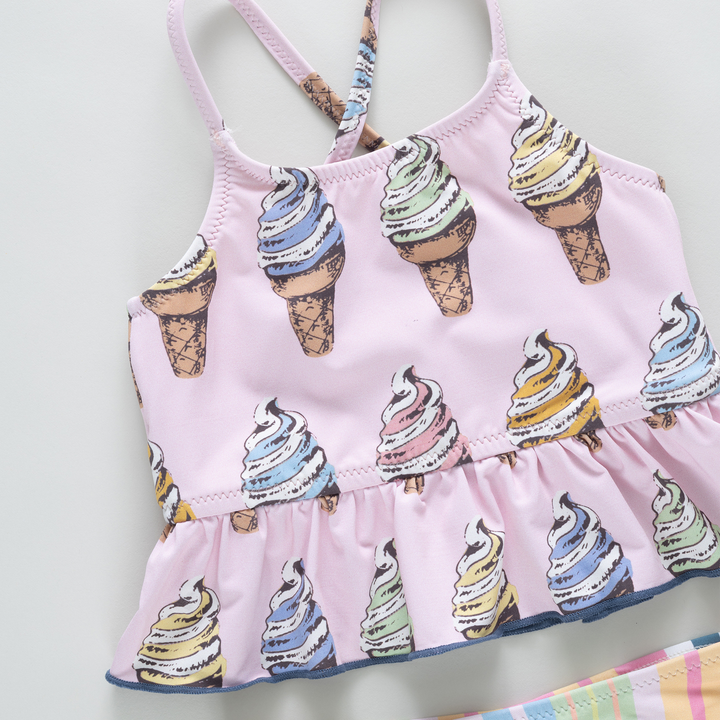 Pink children's swimsuit with ice cream cone pattern on a light gray background