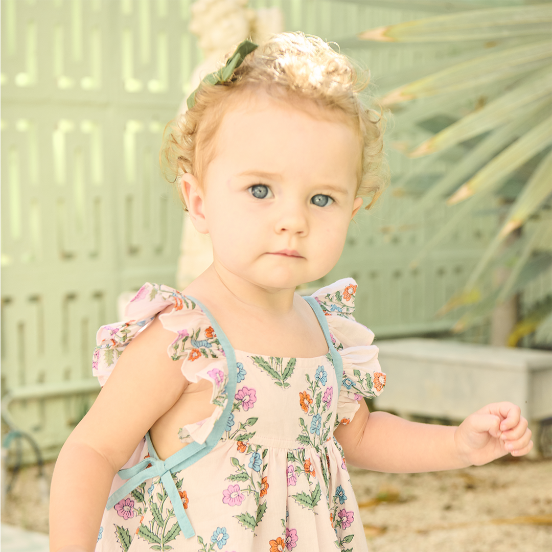Young girl in a floral dress standing outdoors with a blurred background