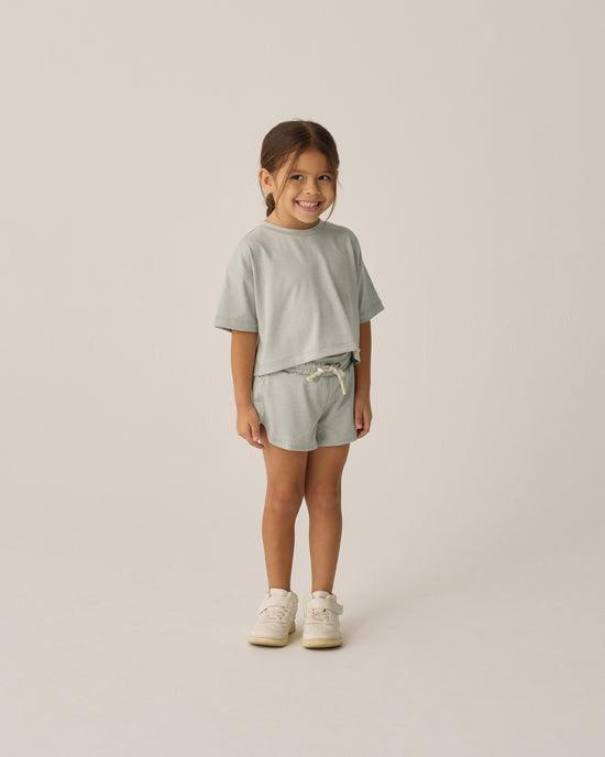 little girl modeling the cropped seafoam green tee shirt and matching shorts. 