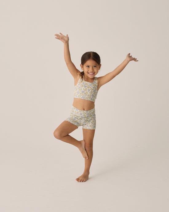 little girl modeling the shorts in bloom print and wearing a coordinating cropped tank top for athletic wear. 