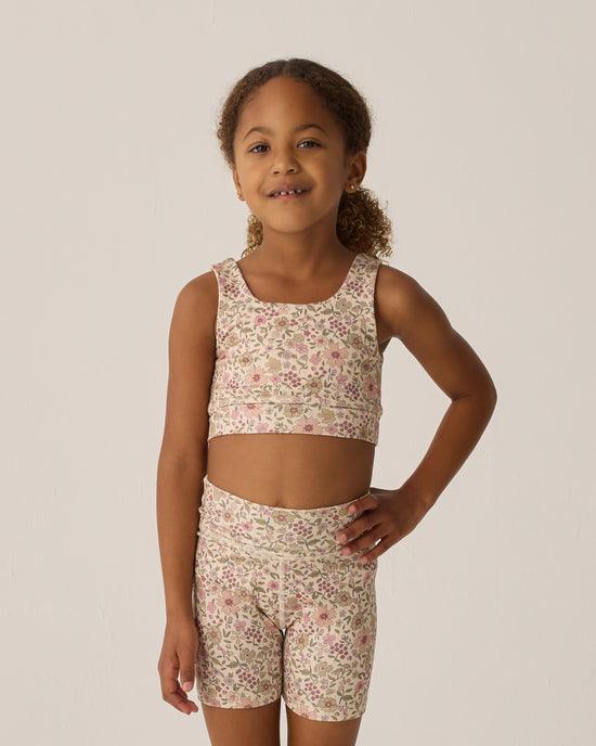 litktle girl wearing a sports bra and bike shorts in matching floral pattern. 