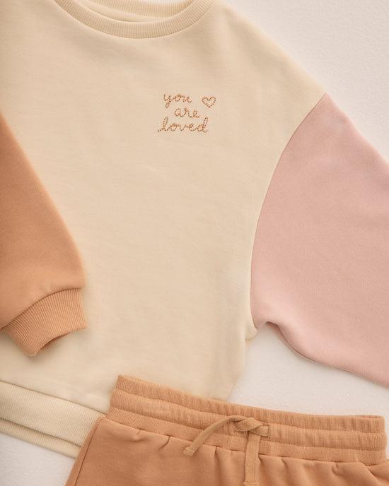close up of the sweatshirt with the stitching that says " you are loved"