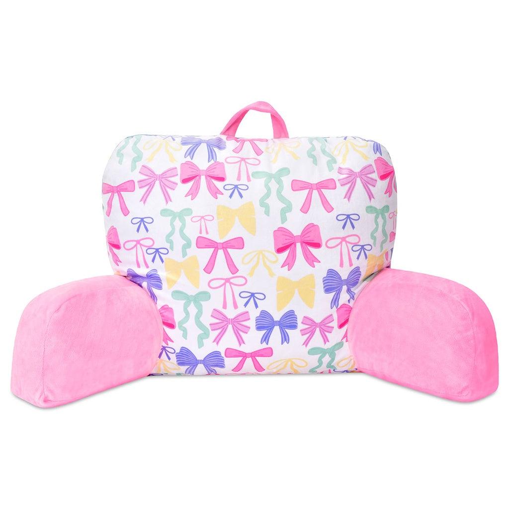 white loungerest pillow with multi color bows along the back and pink arm rests. 