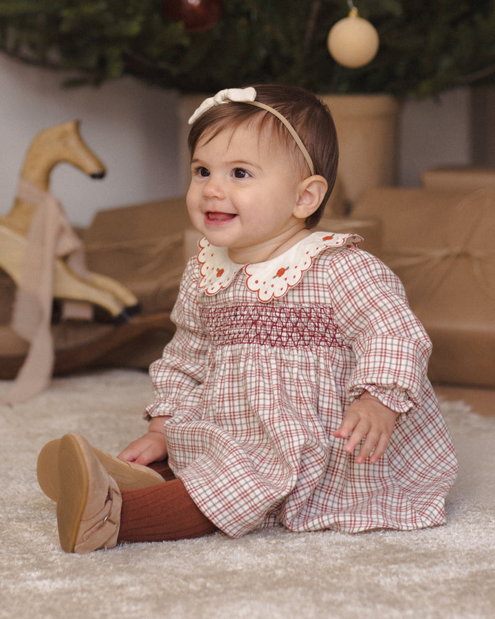 baby wearing a holiday plaid dress. 