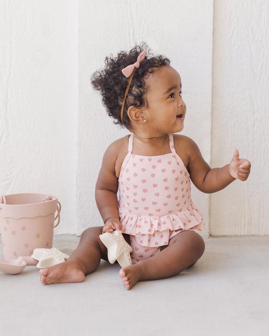 baby girl modeling the pink peplum swimsuit 