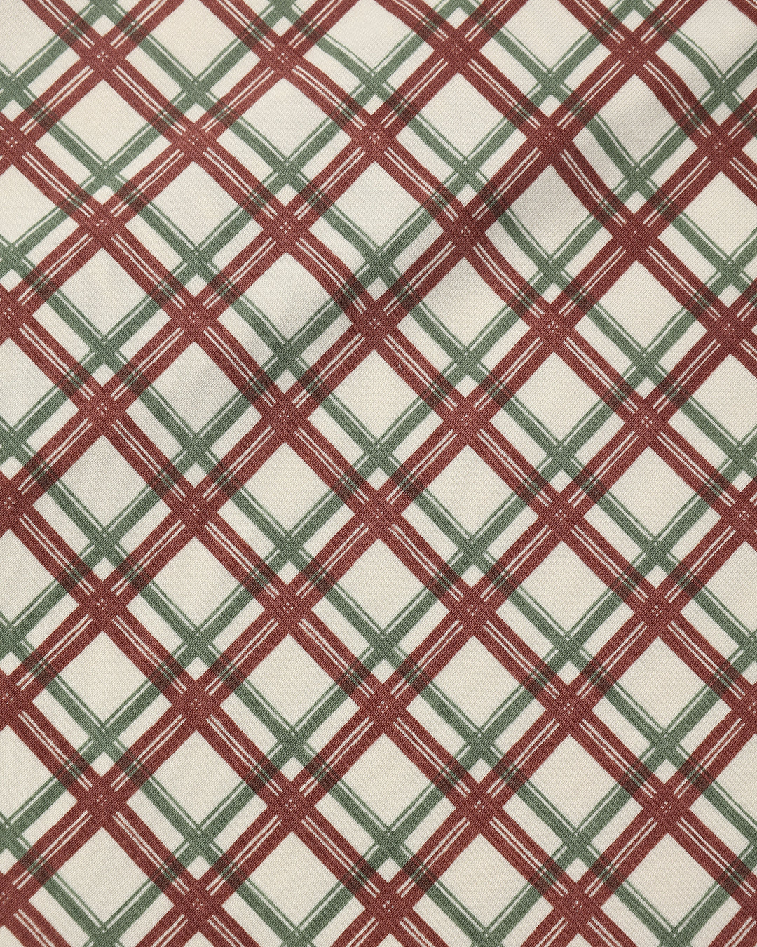 A close-up of a plaid fabric pattern with intersecting diagonal lines in dark red and muted green on an off-white background.