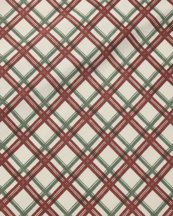 A close-up of a plaid fabric pattern with intersecting diagonal lines in dark red and muted green on an off-white background.