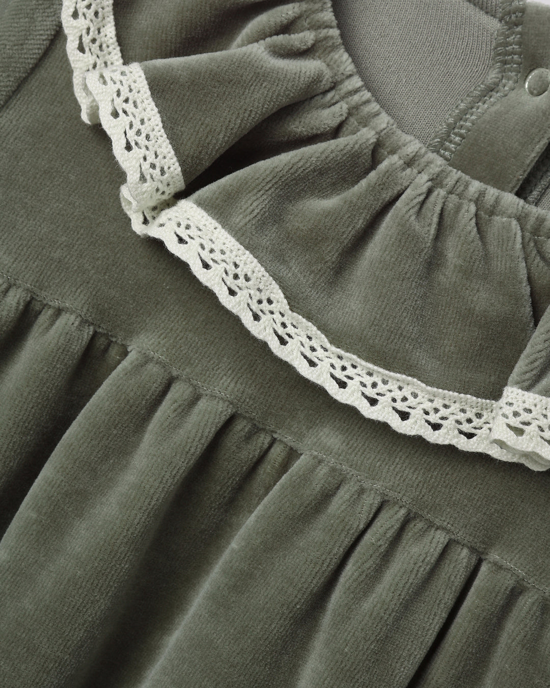 Close-up of a dark olive green dress or nightgown with a gathered neckline and white crochet lace trim.