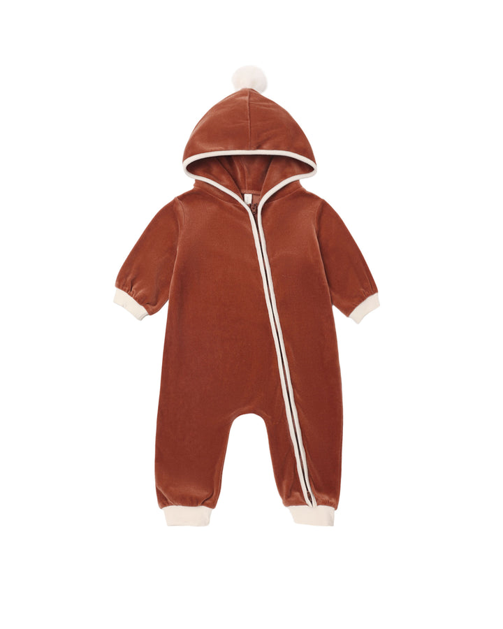 A baby's long-sleeve hooded one-piece romper in rust-red velvet with cream trim, featuring a front zipper, cream cuffs, and a matching cream pom-pom on the hood.