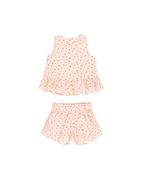 girls set with a peach base color and tiny red cherries all over the set. a peplum at the bottom and elastic waist at the shorts. 